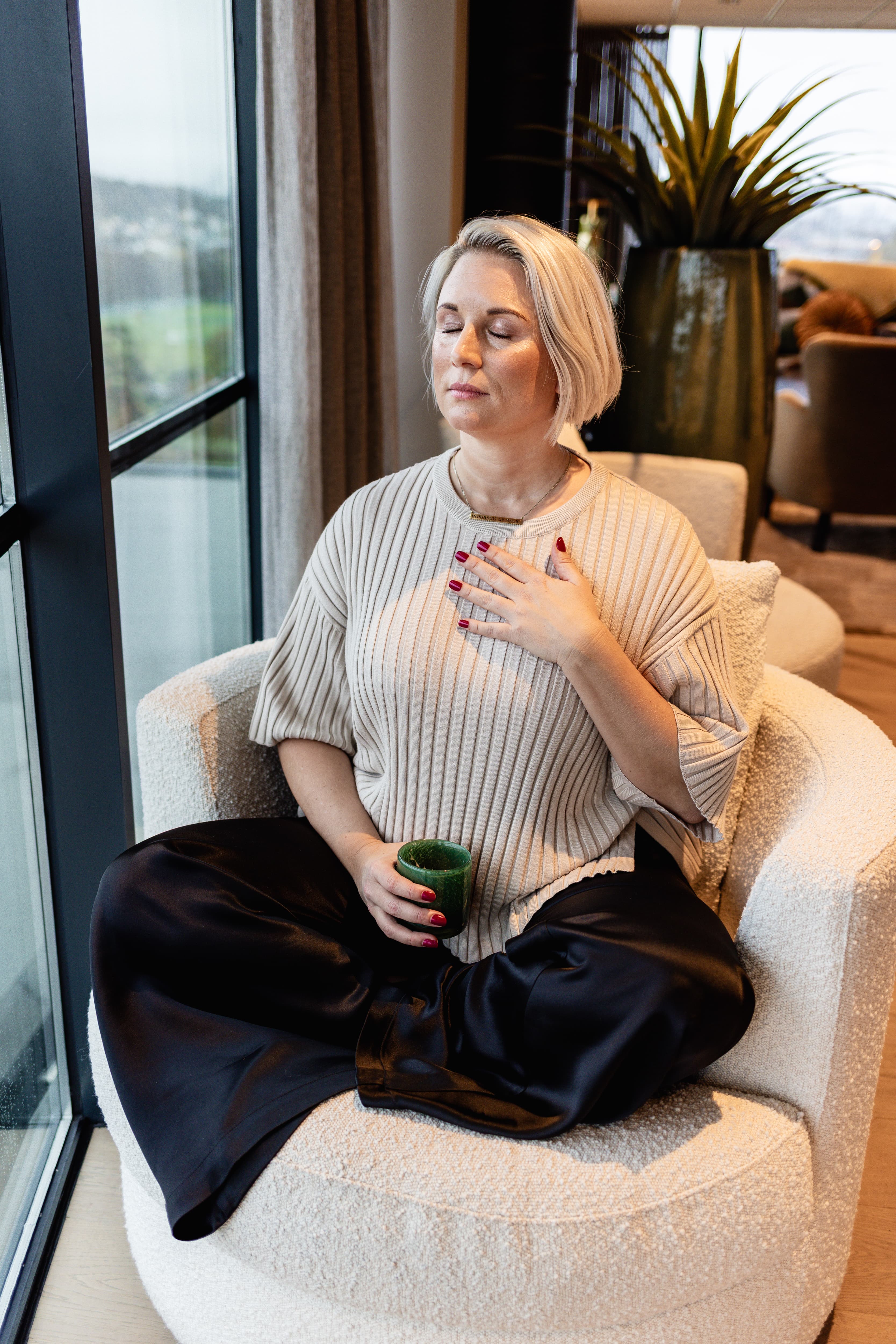 Amanda Randau sitter i fåtölj med handen mot hjärtat – Motståndskraft